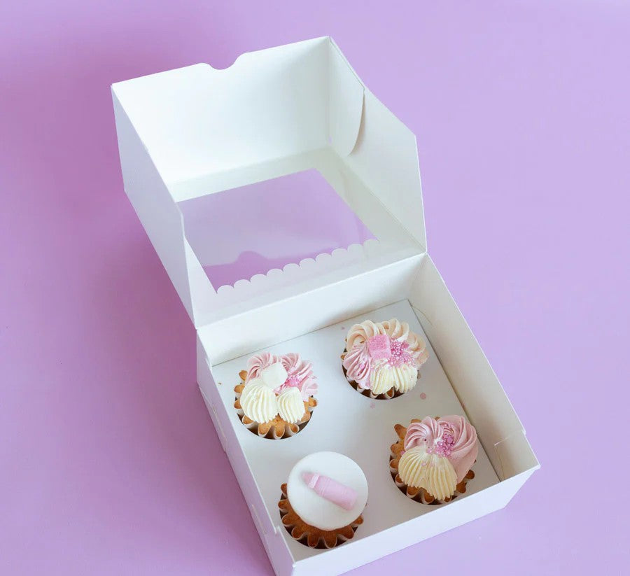 Box of cupcakes with pink and white frosting on a purple background