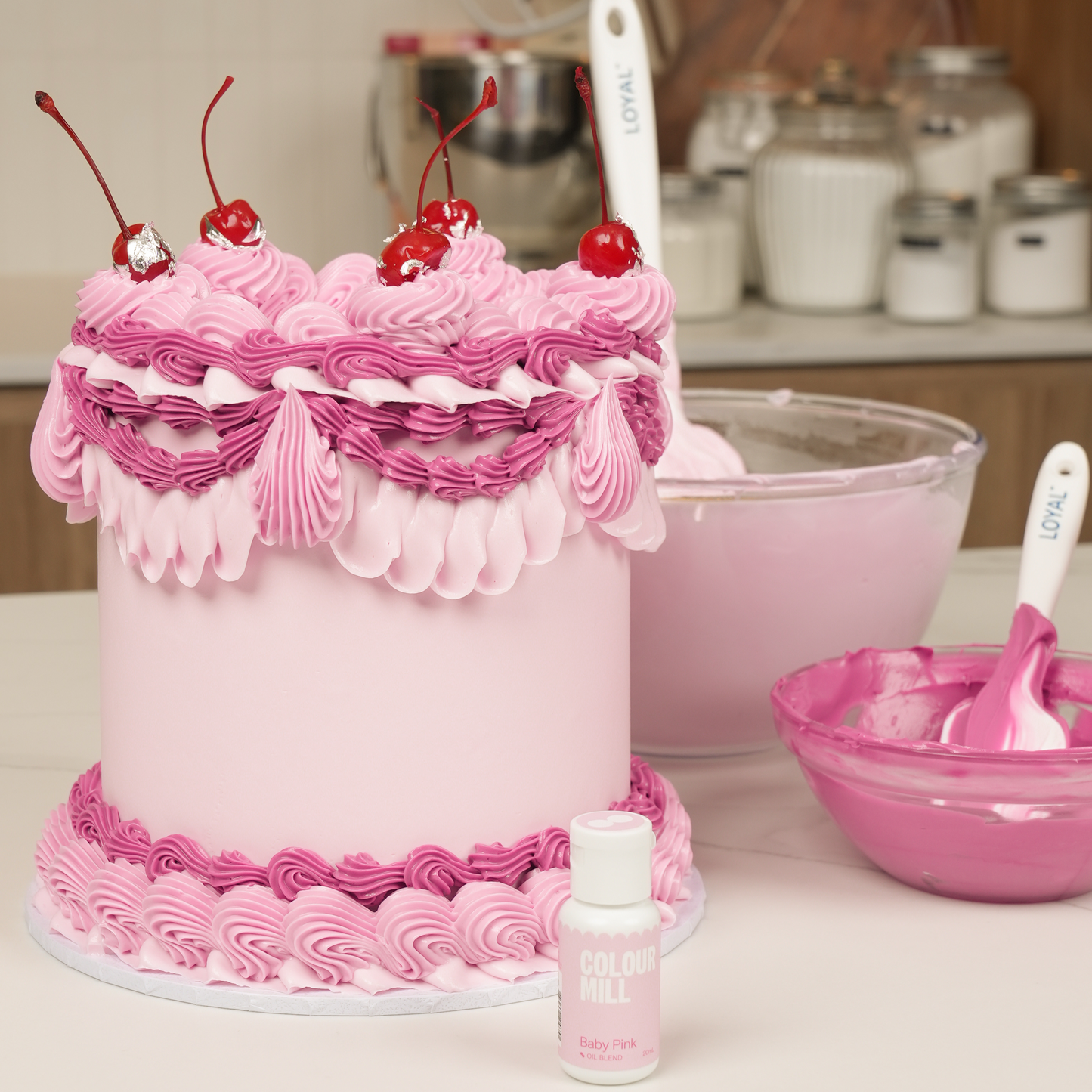 Pink cake with cherry decorations on a kitchen counter