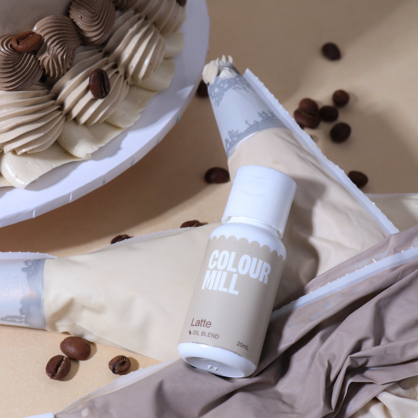Bottle of Colour Mill Latte food coloring with piping bag and cake