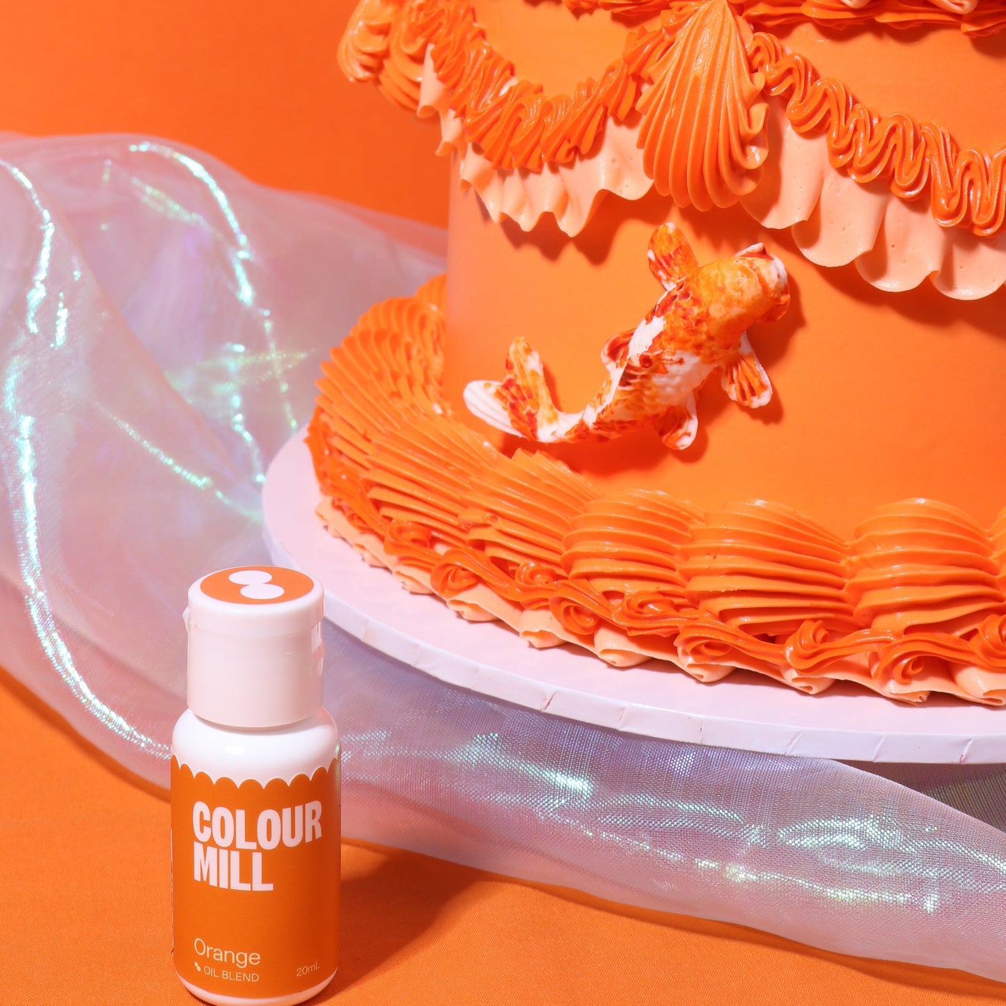 Orange cake with decorative frosting next to a bottle of Colour Mill orange food color on an orange background