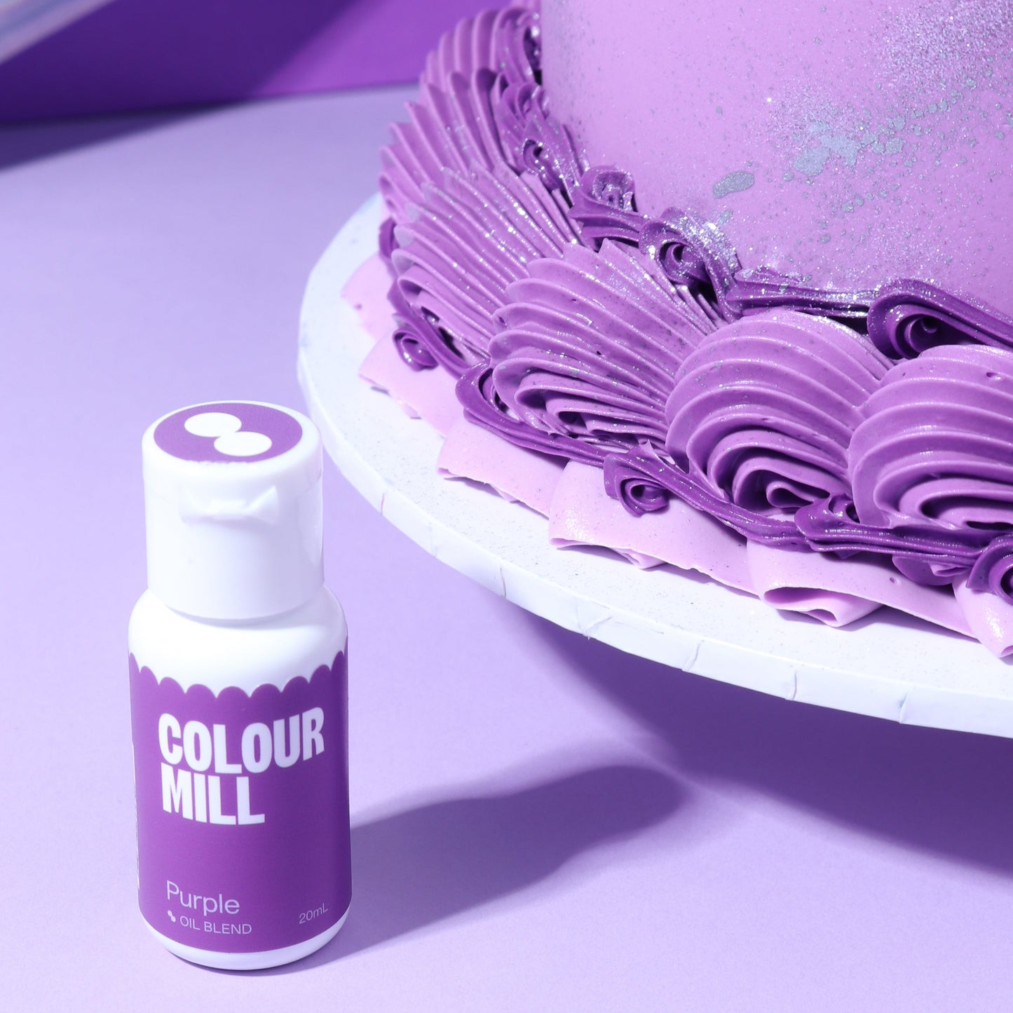 Purple cake with a bottle of Colour Mill purple food colorant on a reflective surface