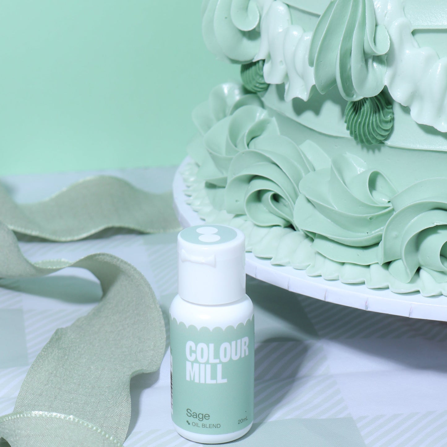 Bottle of Colour Mill Sage hair dye with a decorative green cake in the background
