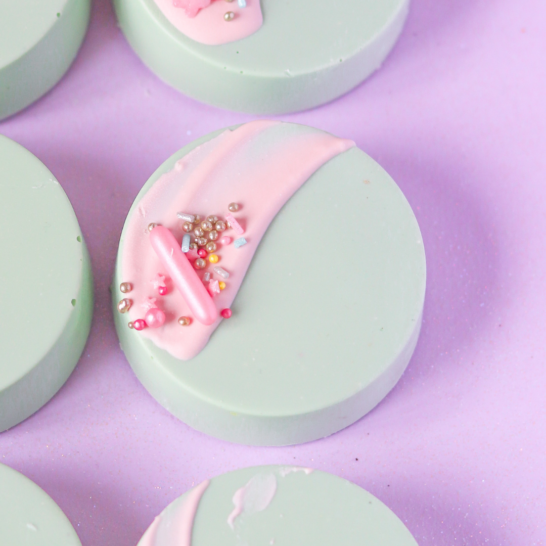 Pastel-colored chocolate with pink center and bead embellishments on a purple background