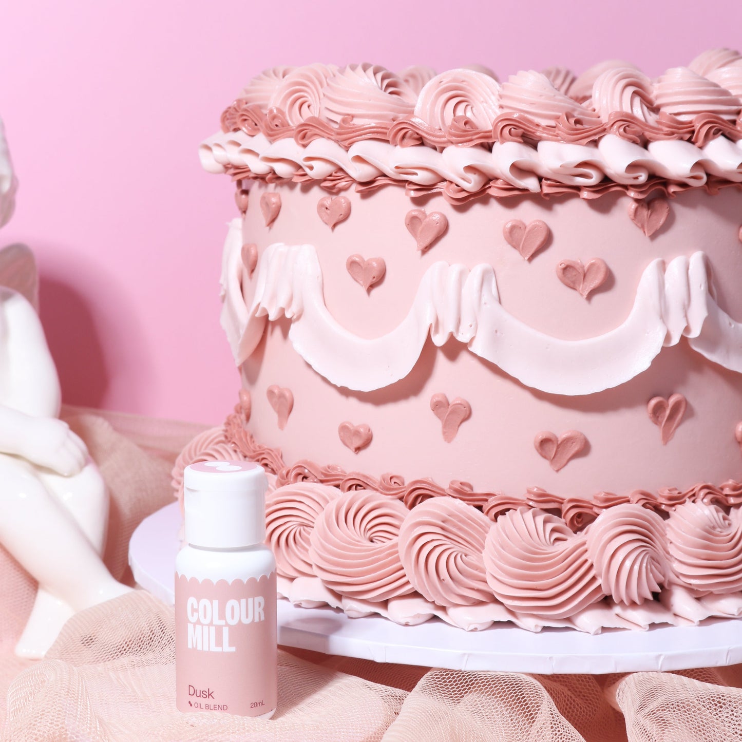 Pink cake with decorative icing and a bottle of Colourful Lipstick on a pink background