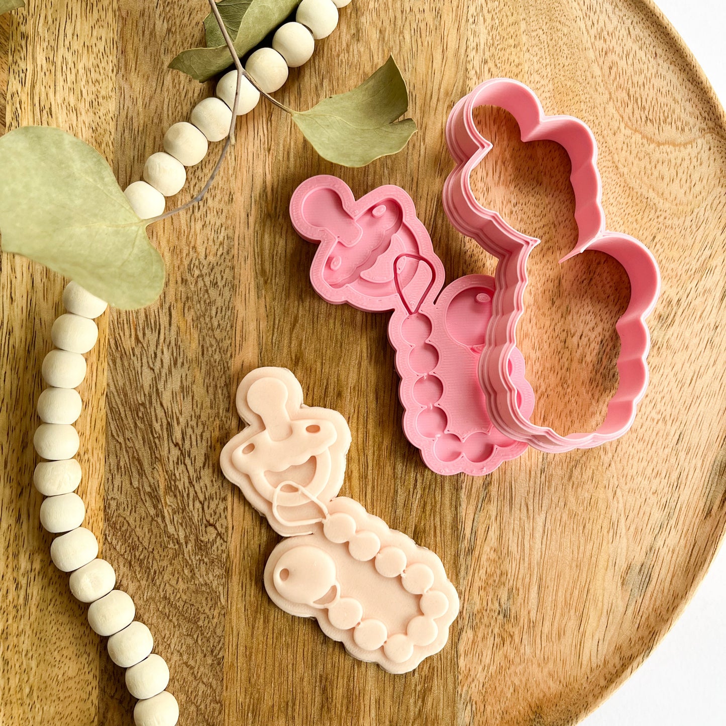 Pacifier cookie cutter and embosser set with rattle-like detail, ideal for decorating cookies for baby showers or newborn parties.