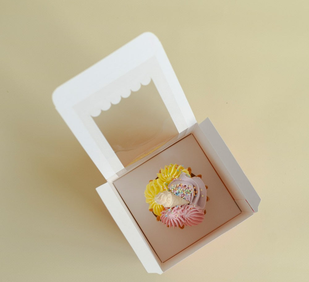 Decorative cupcake in a white box on a beige background