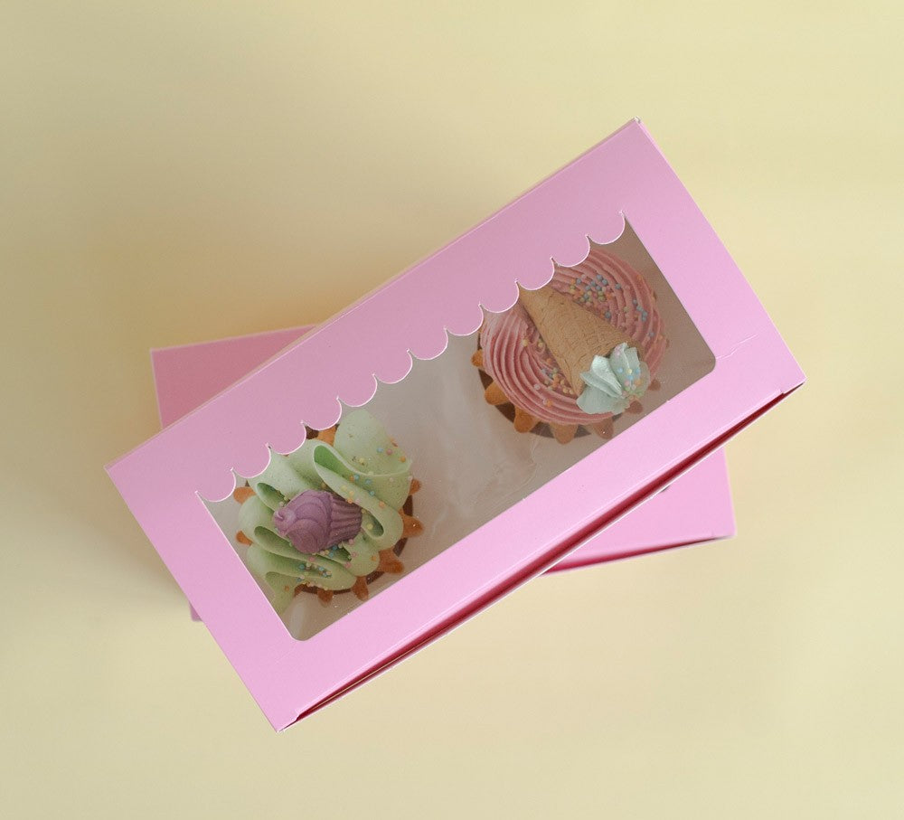 Pink cupcake box with a clear window displaying two cupcakes on a beige background