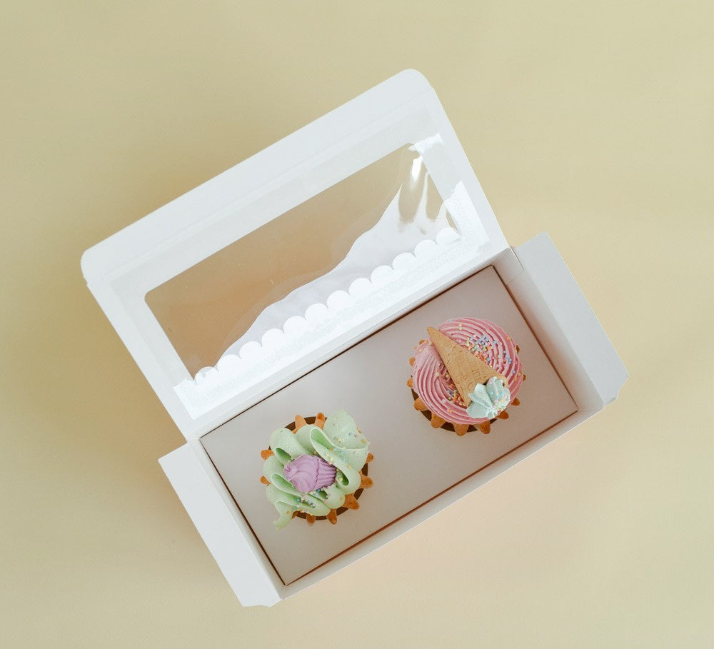 Two small pastries in a white box on a beige background