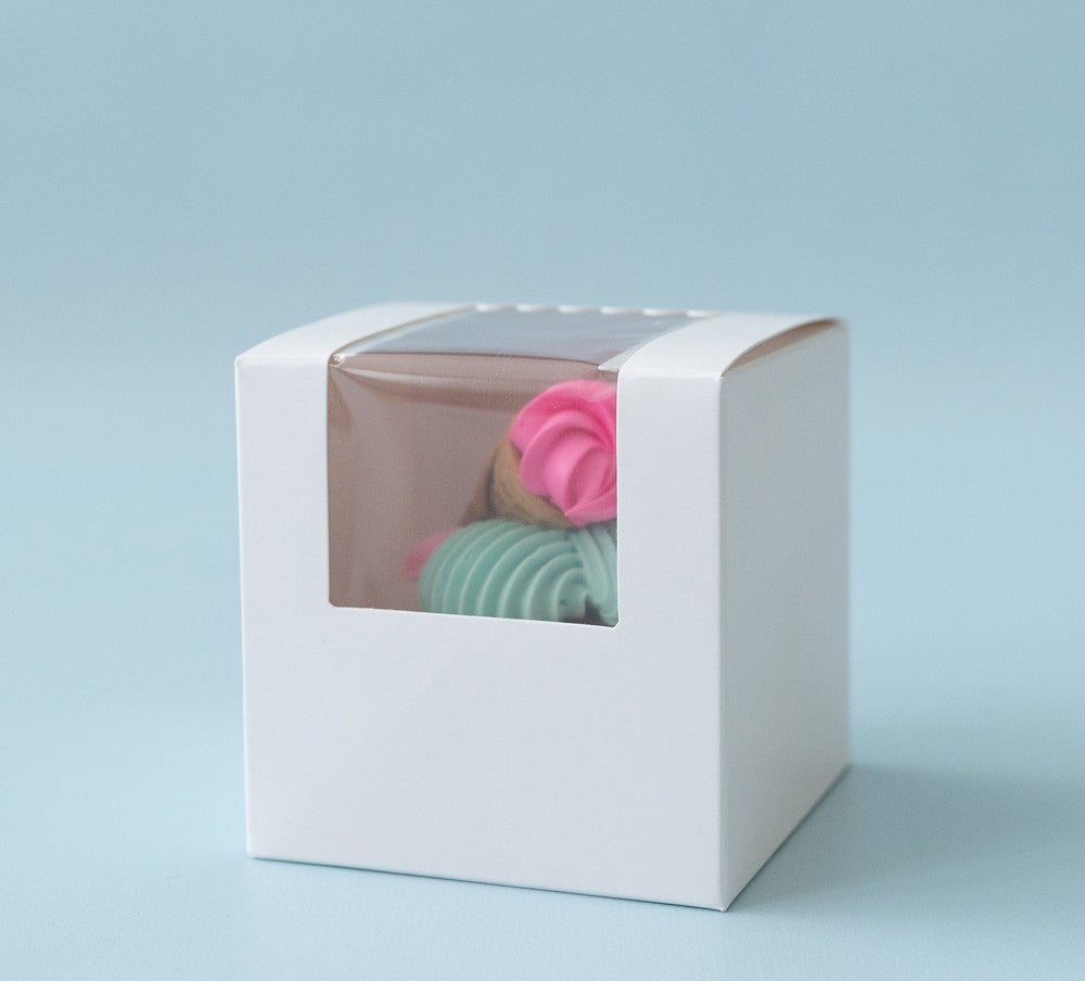 White gift box with a clear window displaying colorful bath bombs on a light blue background