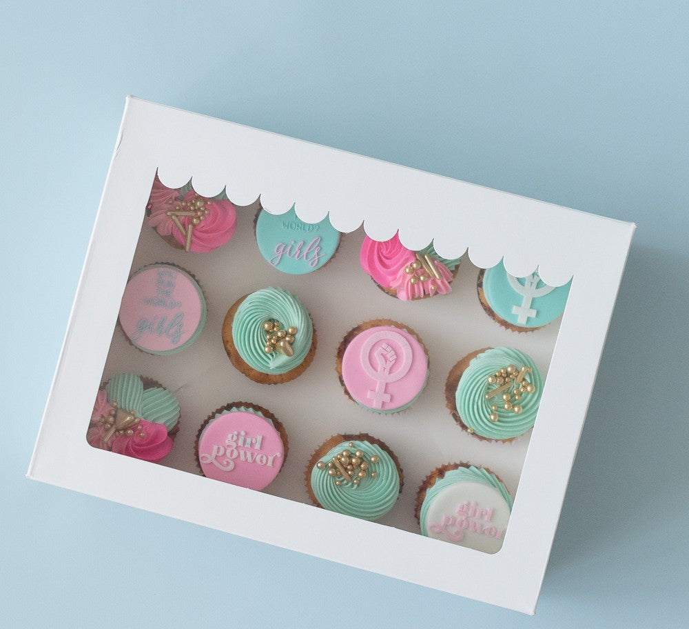 Box of cupcakes with decorative icing and text on a light blue background