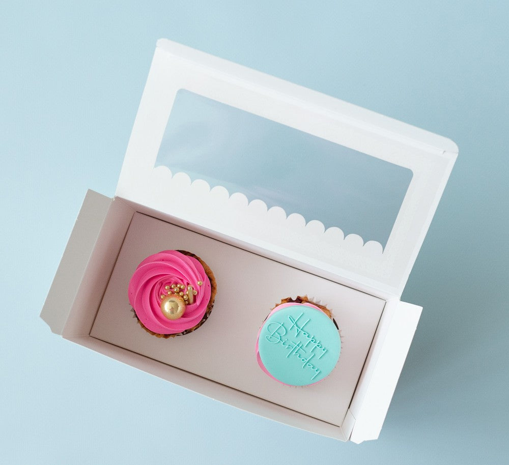 Two cupcakes in a box with a light blue background