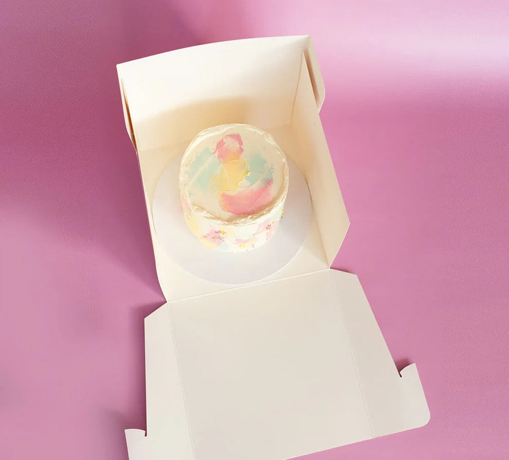 Pastel-colored cupcake in a white box on a pink background