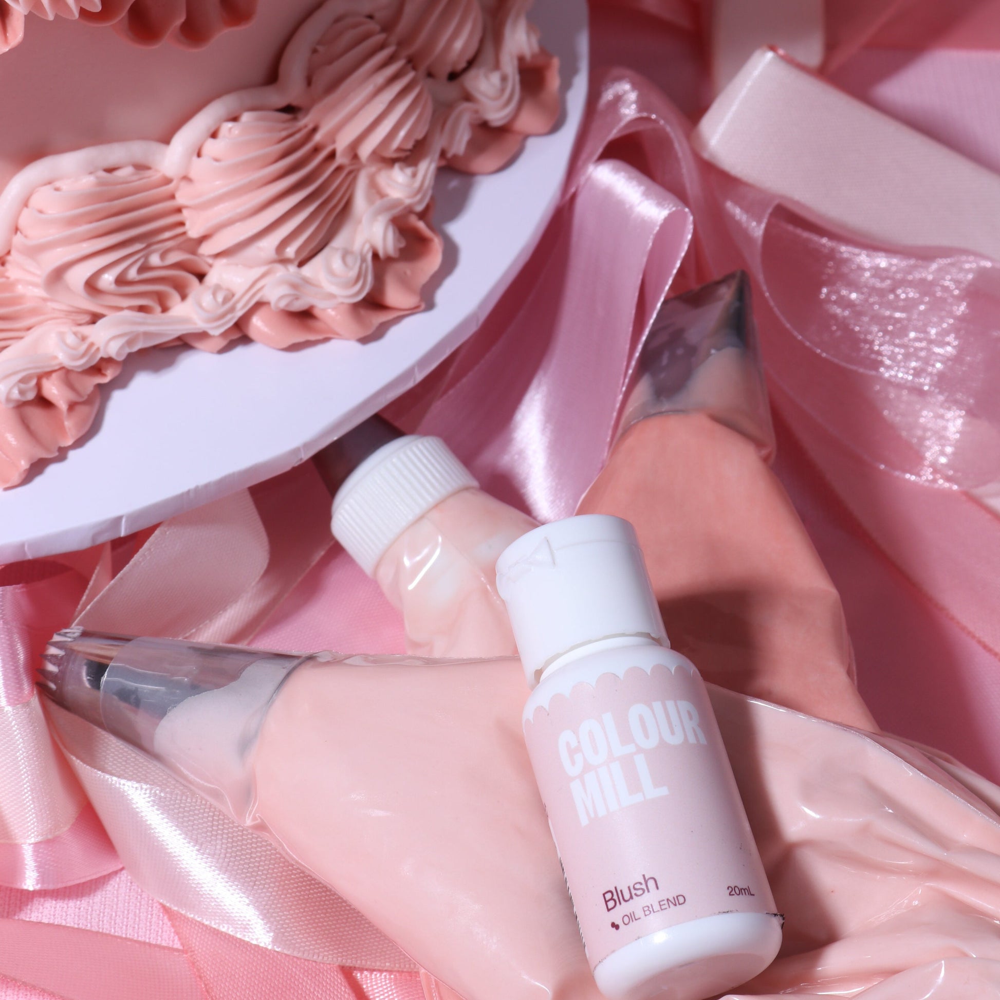 Two skincare bottles with pink and white design on a pink satin background