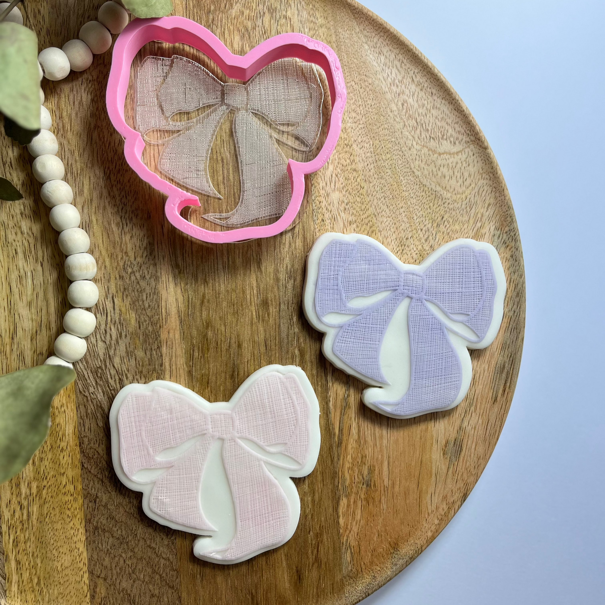 Textured bow cookie cutter and embosser for elegant baking and decorating cookies for gifts or parties.