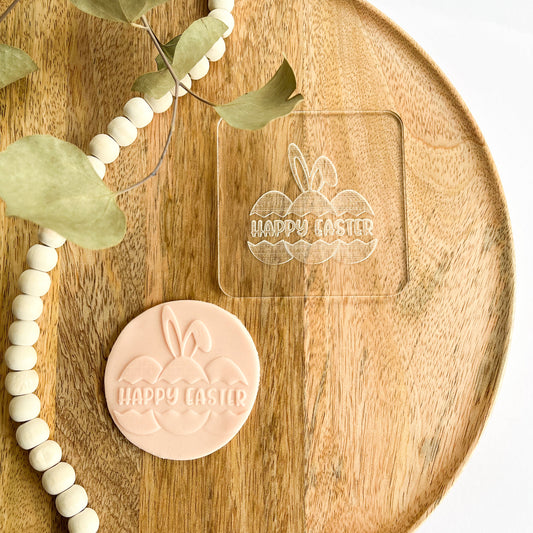 Cookie embosser with Happy Easter text and bunny ears over Easter eggs, perfect for spring baking and festive cookie decorating.
