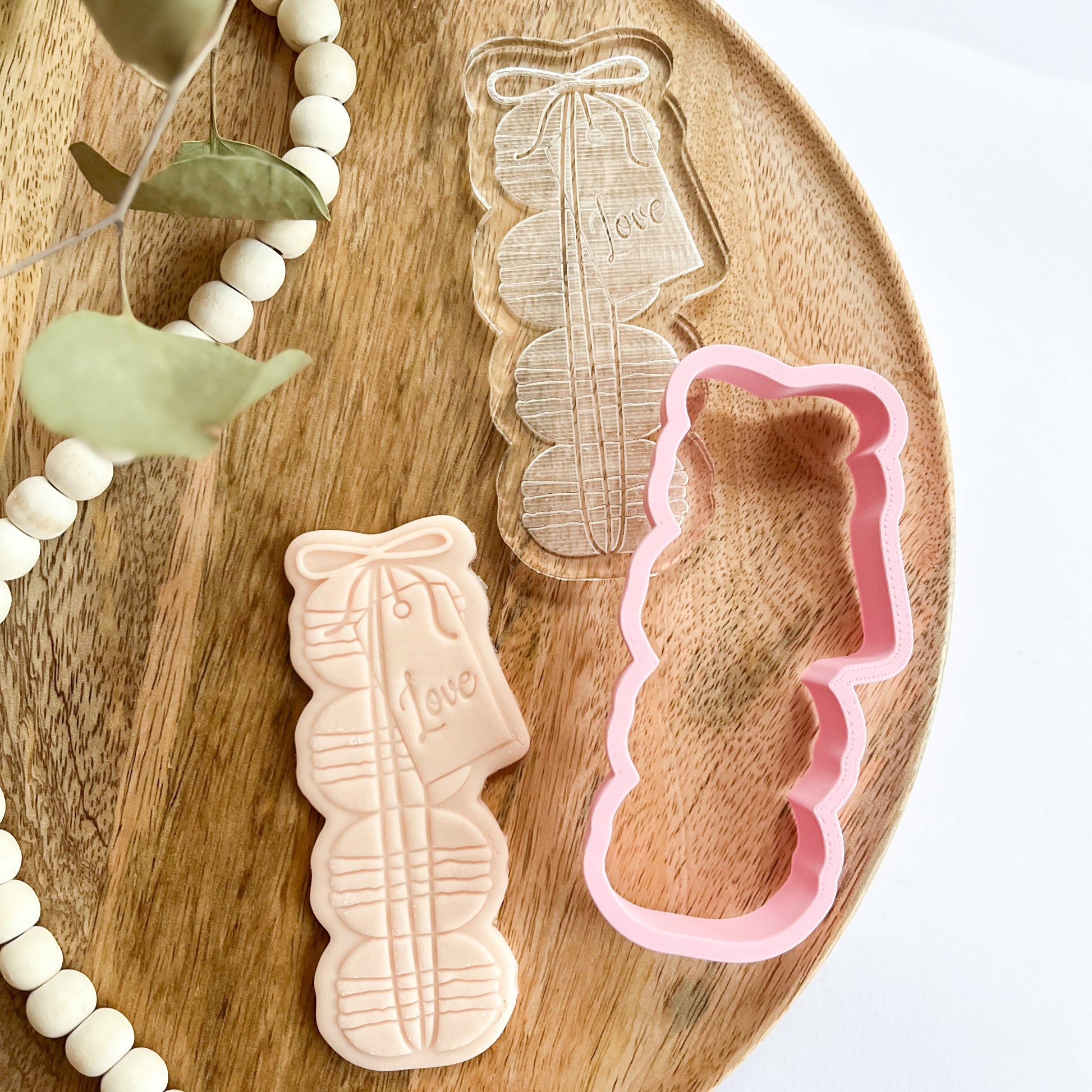 Macaron stack cookie cutter and embosser with “Love” tag, ideal for romantic cookie decorating or wedding treats.
