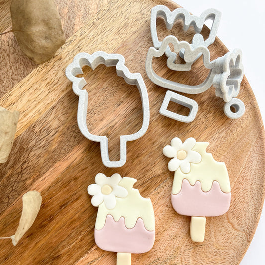 Set of cookie cutters shaped like ice cream cones and popsicles on a wooden board.