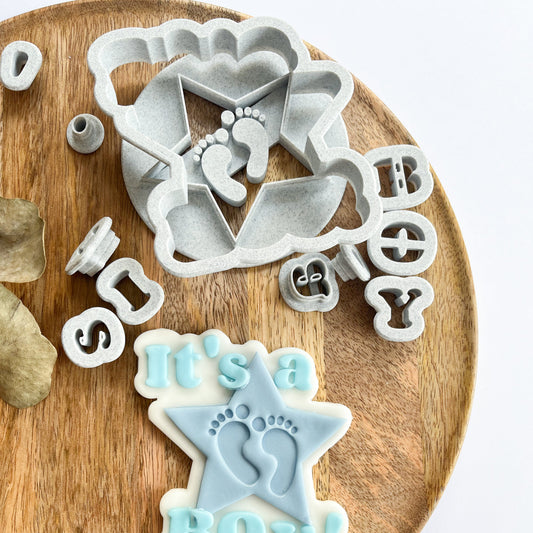 Set of cookie cutters with baby-themed designs on a wooden board