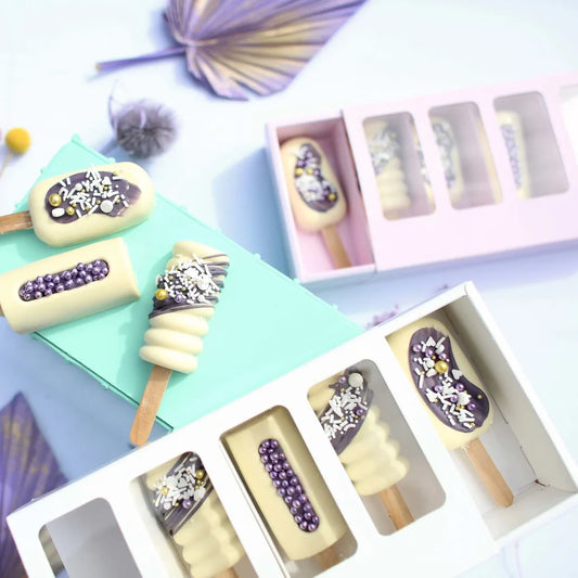 Decorative ice cream popsicles in a box with a fan in the background