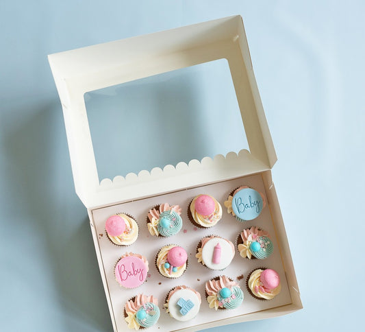 Box of small cupcakes with 'Baby' writing on a light blue background